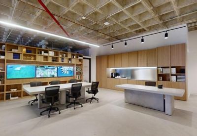 Communal break area with wooden cabinetry, a long white table, and multiple monitors set against a grid ceiling.