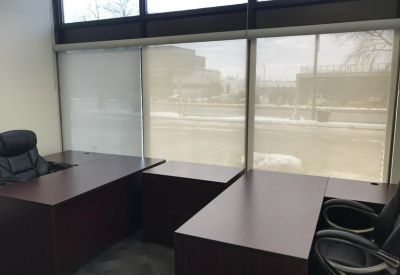 Private office suite featuring dark wood desks and large windows with blinds.