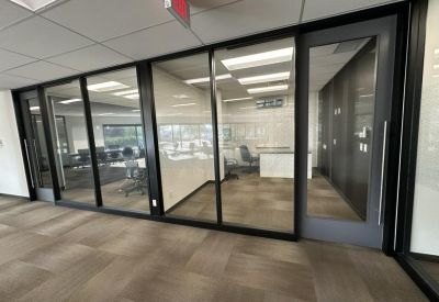 Internal view of a glass-walled meeting room showing a white table and black chairs.