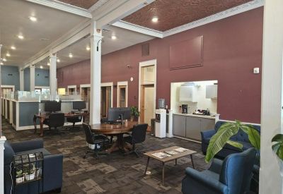 Lounge area with blue armchairs and a small kitchen prep space in the background.