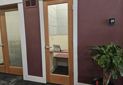 Private phone booth or study nook with a glass door and wooden trim.