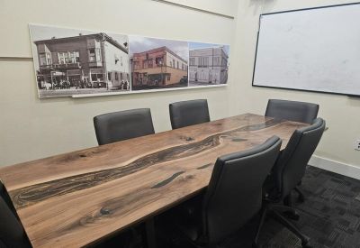 Close-up of a natural wood conference table with black executive chairs.