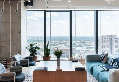 Lounge area with grey armchairs and floor-to-ceiling windows overlooking the city.