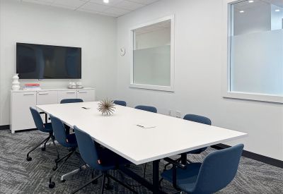 Meeting room at 61 West Palisade Avenue, 2B, Englewood with a white conference table, blue chairs, and a wall-mounted TV.