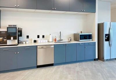 Modern communal kitchen with blue cabinetry and stainless steel appliances.
