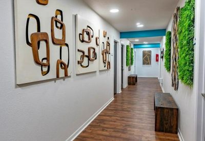 Long corridor with warm wood flooring, abstract wall art, and vertical moss feature walls.