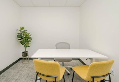 Private office suite with a white desk, grey task chair, and two yellow visitor chairs.