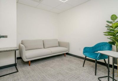 Modern breakout room featuring a light grey sofa and a teal accent chair.