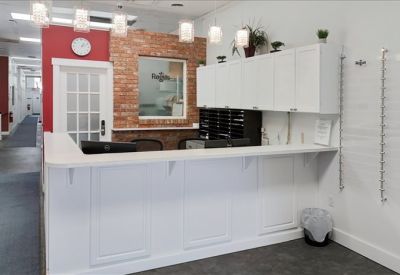 Bright reception desk area with a brick accent wall and white counter.