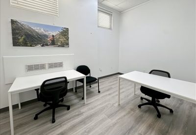 Minimalist two-person private office with white desks and landscape wall art.