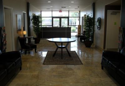 Spacious building lobby with a central round table, indoor plants, and polished floors.