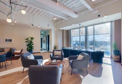 Modern lobby area with grey armchairs, a marble-top table, and floor-to-ceiling windows.