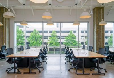 Workspace featuring large tables and black ergonomic chairs overlooking greenery.