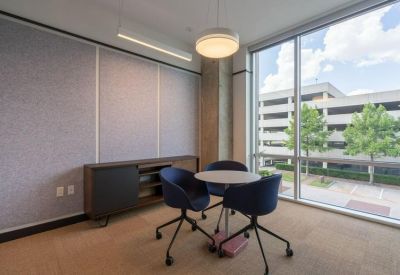 Small meeting area with a round table, blue chairs, and large window views.