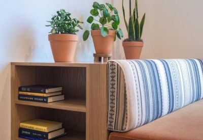 Wooden bookshelf and bench seating with blue striped cushions and potted plants.