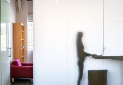 Silhouette of a person working at a standing desk behind a frosted glass partition.
