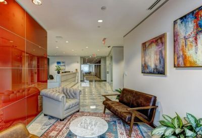 Reception area featuring leather furniture and abstract artwork on white walls.