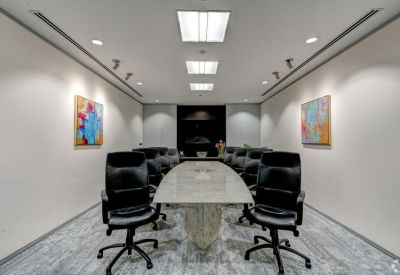Modern conference room with a large white table and black leather chairs.