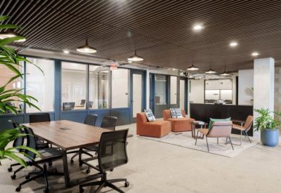 Bright reception and lounge area with orange armchairs and a sleek black front desk.