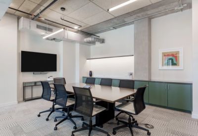 Professional conference room with a large wooden table, black chairs, and a wall-mounted TV.