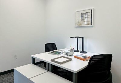Small private office suite with a white desk, black mesh chairs, and framed wall art.