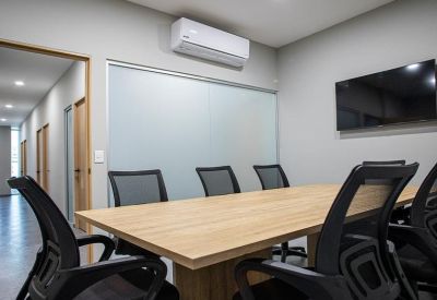 Spacious boardroom with a large wooden table, wall-mounted TV, and air conditioning unit.