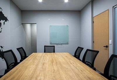 Modern conference room with a long wooden table, black mesh chairs, and a whiteboard.
