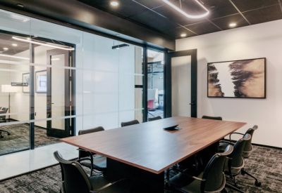 Modern conference room with a large wooden table and black ergonomic chairs.