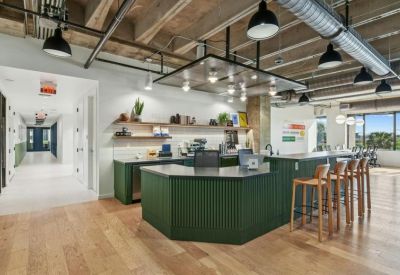 Modern reception area with a green slatted desk and industrial ceiling.