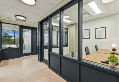 Glass-walled private offices along a bright hallway with navy blue accents.