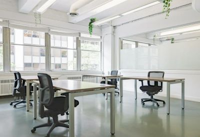 Bright shared workspace with multiple desks and ergonomic chairs.