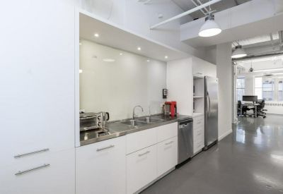 Long white kitchen featuring stainless steel appliances and minimalist cabinetry.