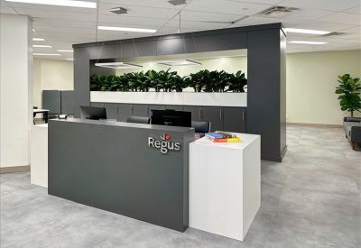 Contemporary reception area with a dark gray desk, Regus branding, and built-in planters.
