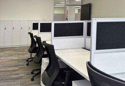 Row of modern workstations with ergonomic chairs and privacy partitions.
