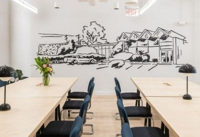 Minimalist meeting area with light wood tables and a large architectural wall mural.