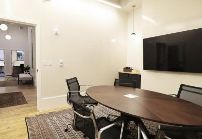 Small meeting room with an oval dark wood table and black mesh chairs.