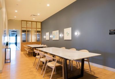 Long marble conference table in a room with grey walls and framed abstract art.