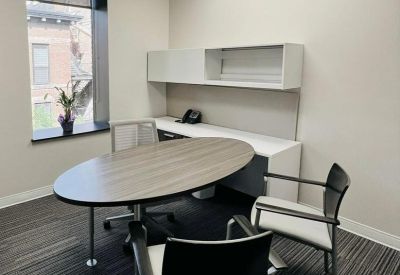 Bright workspace featuring an oval meeting table, grey carpet and sleek overhead storage.