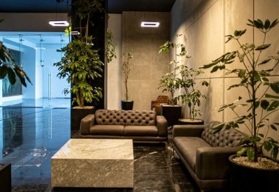 Moody communal lounge featuring dark leather sofas and tall indoor plants.