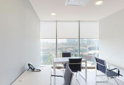 Bright office space with white desks and black ergonomic chairs overlooking the city.