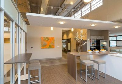 Breakout area with high-top tables, bar stools, and a vibrant orange painting.