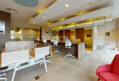 Modern lounge and reception area with a red armchair and white desks against a brown accent wall.