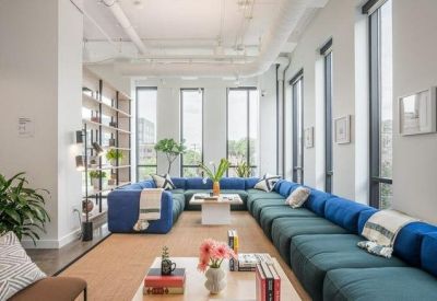 Lounge area featuring an exceptionally long blue sectional sofa and floor-to-ceiling windows.