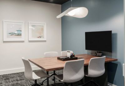 Small meeting room with a wooden table, gray chairs, and a blue accent wall.