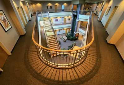 Elevated view of a multi-level indoor atrium with a central staircase and glass railings.