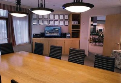 Spacious boardroom featuring a long wood table, modern black chairs, and framed artwork on the walls.