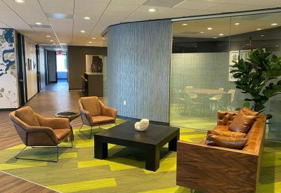 Lounge area with leather armchairs and a wood-paneled sofa on a green patterned rug.