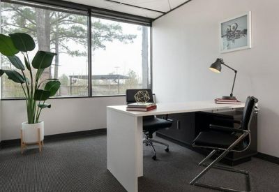 Private office featuring a white L-shaped desk, black leather chairs, and a large window.