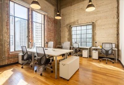 Spacious open-plan workspace with white desks, ergonomic chairs, and exposed brick walls.
