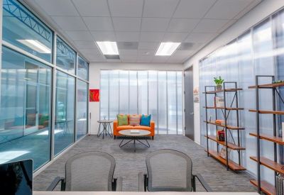 Bright reception seating area with an orange sofa and translucent partitions.